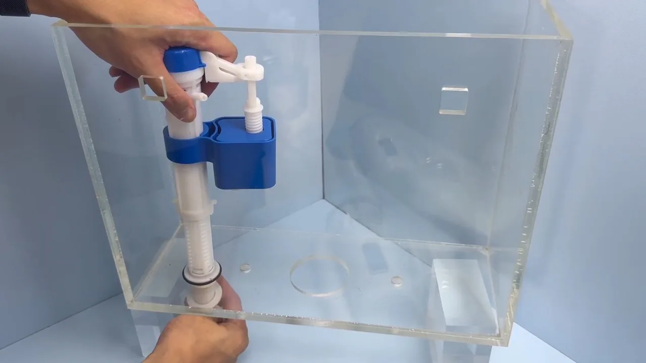 Hands setting a blue and white fill valve into a clear acrylic toilet tank