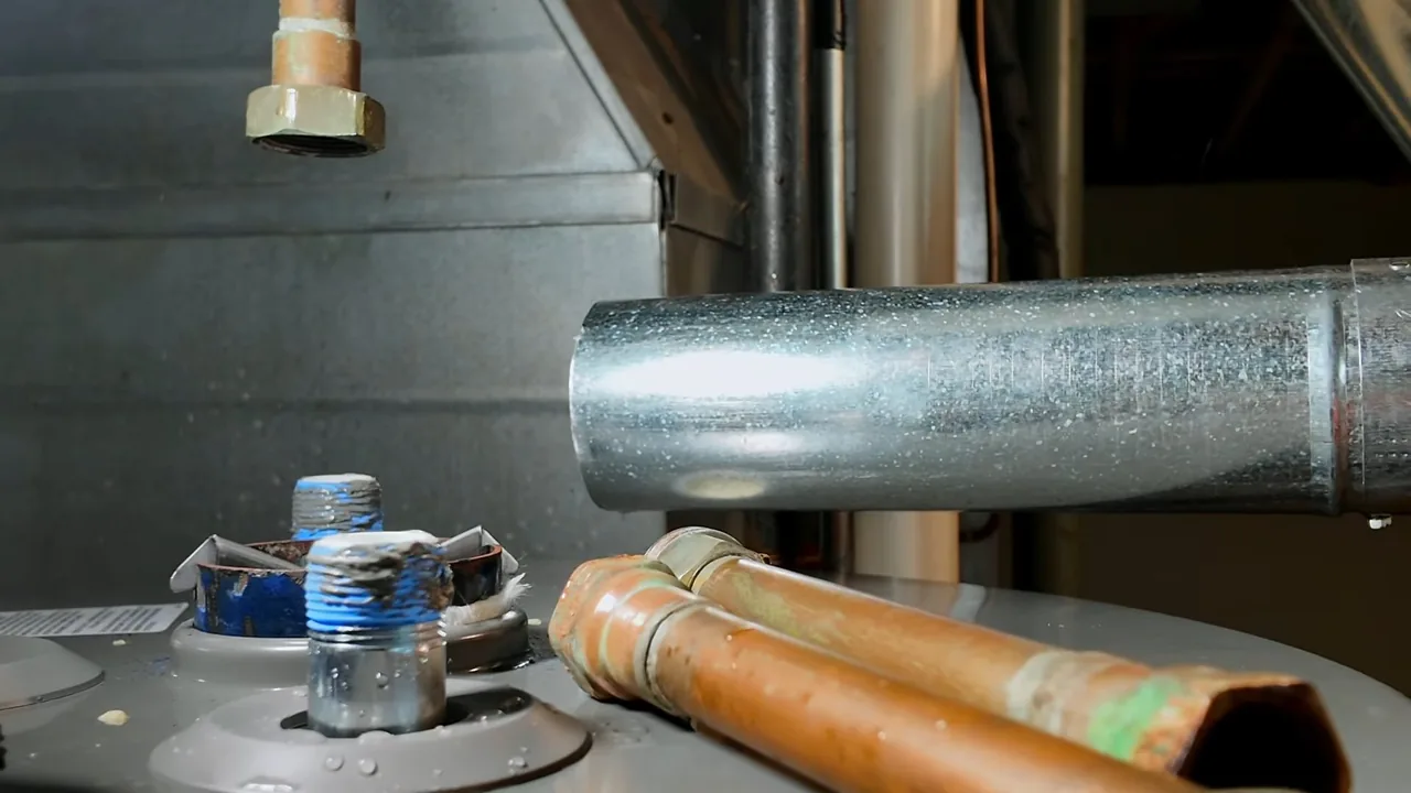 The top of a tank water heater with a galvanized vent pipe, capped fittings and copper lines